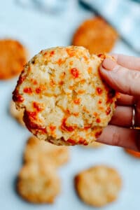 Hand holding an Italian biscuit with more biscuits in background.